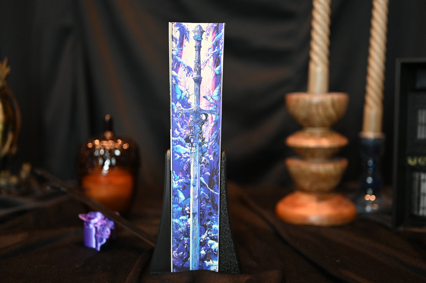 Cartea Quicksilver de Callie Hart, ediție specială cu margini imprimate (printed edges) în nuanțe de violet și albastru, ilustrând o sabie magică într-o pădure fantasy.