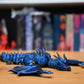 Figurina 3D articulată Figurina dragon albastru metalic articulat, cu ochi violet și detalii realiste, decor fantasy pentru birou sau bibliotecă.