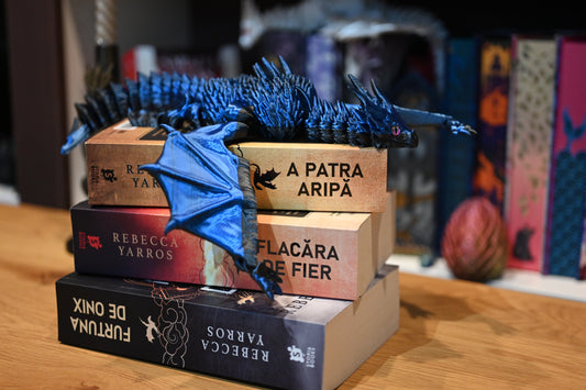 Figurina 3D articulată Dragon albastru articulat așezat pe romanele „A Patra Aripă” de Rebecca Yarros, decor perfect pentru pasionații de lectură și fantezie.