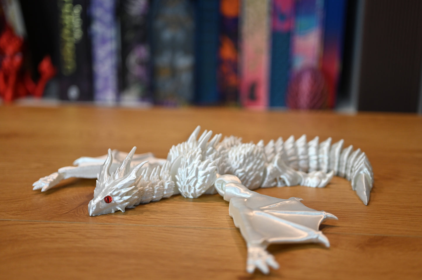 Figurina dragon alb perlat cu ochi roșii, model articulat imprimat 3D, decor fantasy elegant pentru colecționari.
