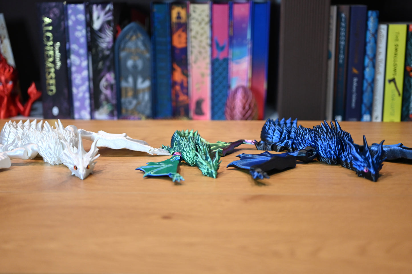 Set de trei dragoni decorativi — alb perlat, verde iridescent și albastru metalic — figurine articulate 3D pentru decor fantasy și colecționari.