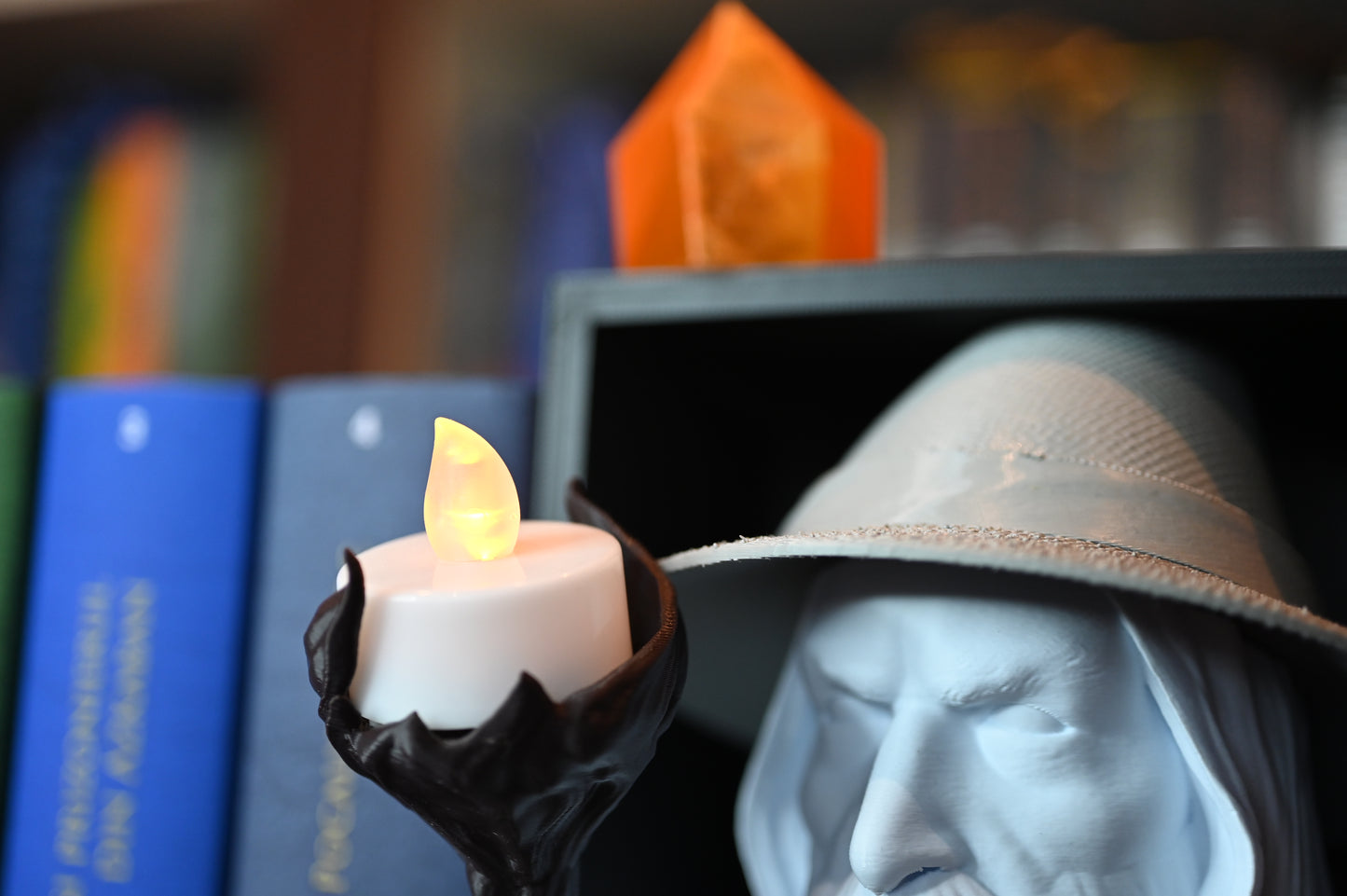 lumanare led plasata pe toiagul vrajitorului inspirat din Gandalf între volumele colorate ale seriei Harry Potter pe un raft de cărți.