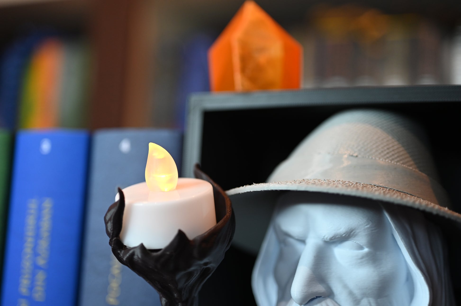 lumanare led plasata pe toiagul vrajitorului inspirat din Gandalf între volumele colorate ale seriei Harry Potter pe un raft de cărți.