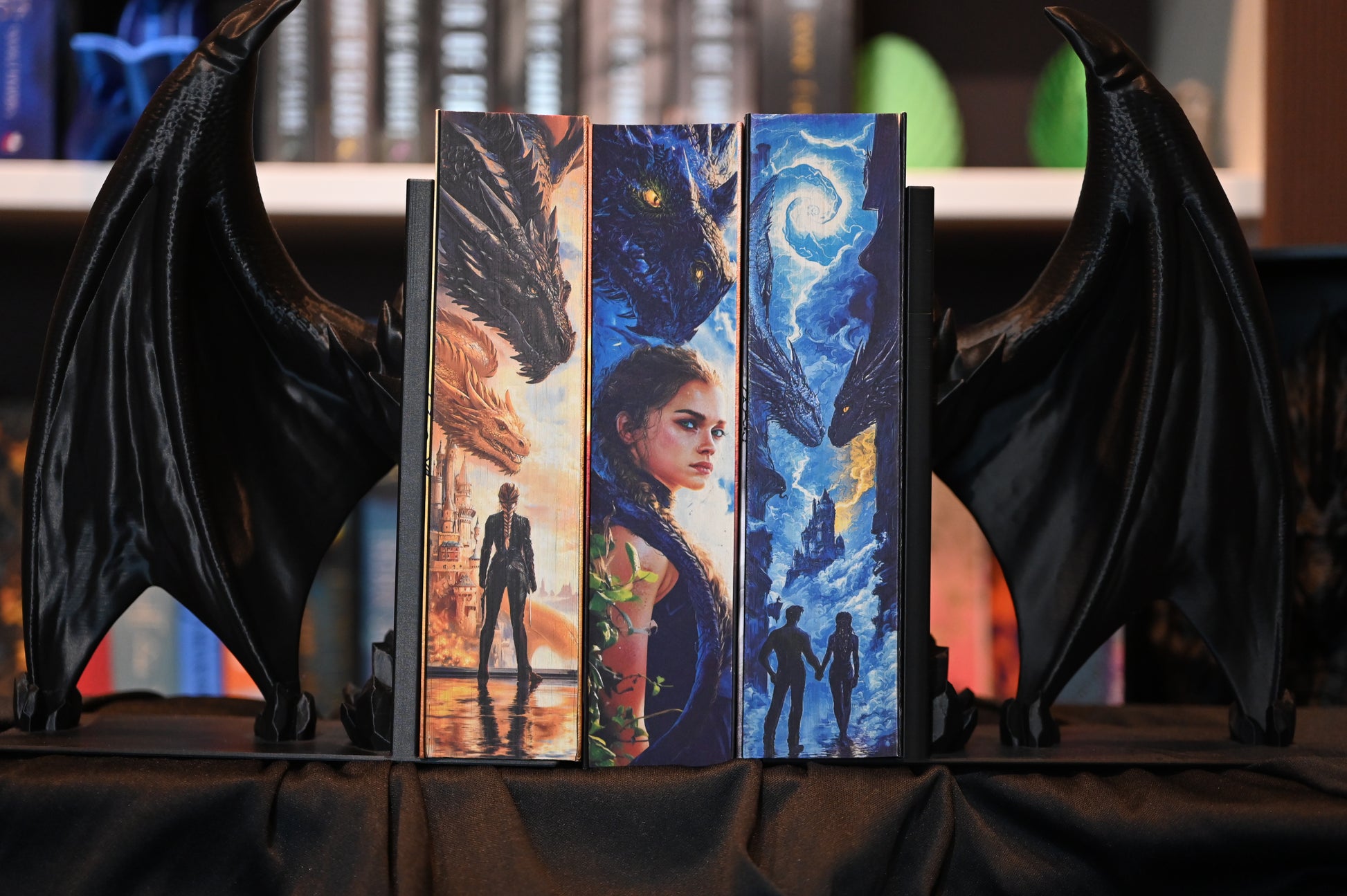 Seria completă Empyrean de Rebecca Yarros – „A patra aripă”, „Flacăra de fier” și „Furtuna de onix” – ediții speciale cu printed edges realizate de Printedges. Marginea fiecărei cărți formează o imagine continuă cu dragoni, cer în flăcări și personaje fantasy, așezate între suporturi negre în formă de aripi de dragon.