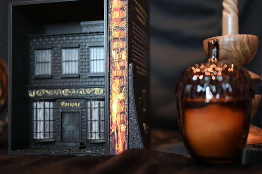 design Culegătorul de povești cu printed edges cu bibliotecă magică și lumini calde aurii, alături de decor fantasy negru și auriu.