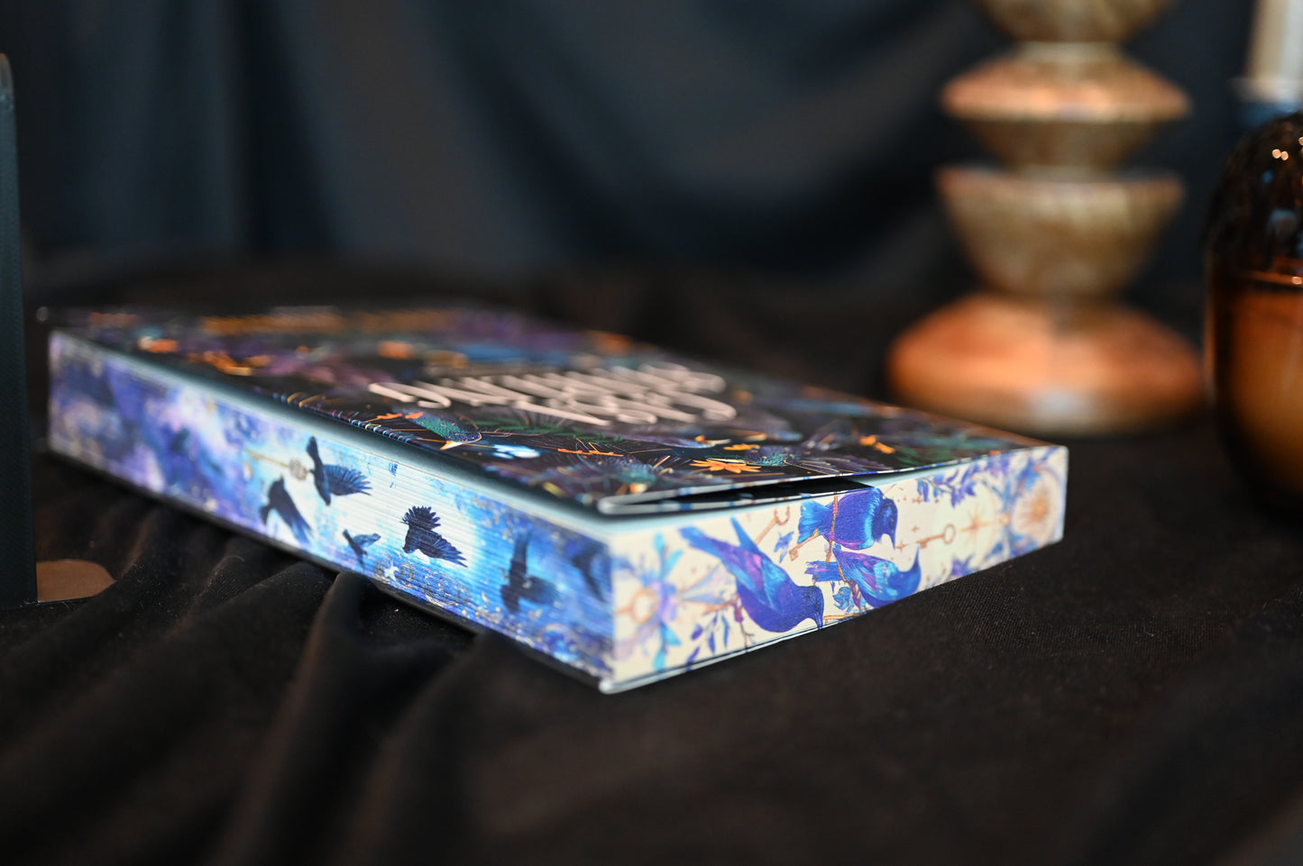 Casa Starling cu printed edges de Alix E. Harrow, ediție specială cu margini imprimate (printed edges) ilustrate cu păsări albastre și fundal nocturn, expusă într-un decor elegant.