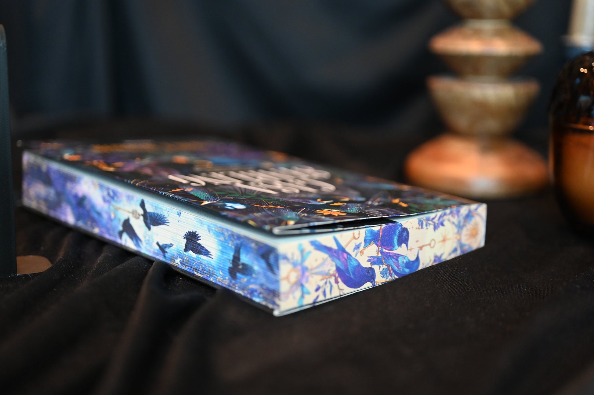 Casa Starling cu printed edges de Alix E. Harrow, ediție specială cu margini imprimate (printed edges) ilustrate cu păsări albastre și fundal nocturn, expusă într-un decor elegant.