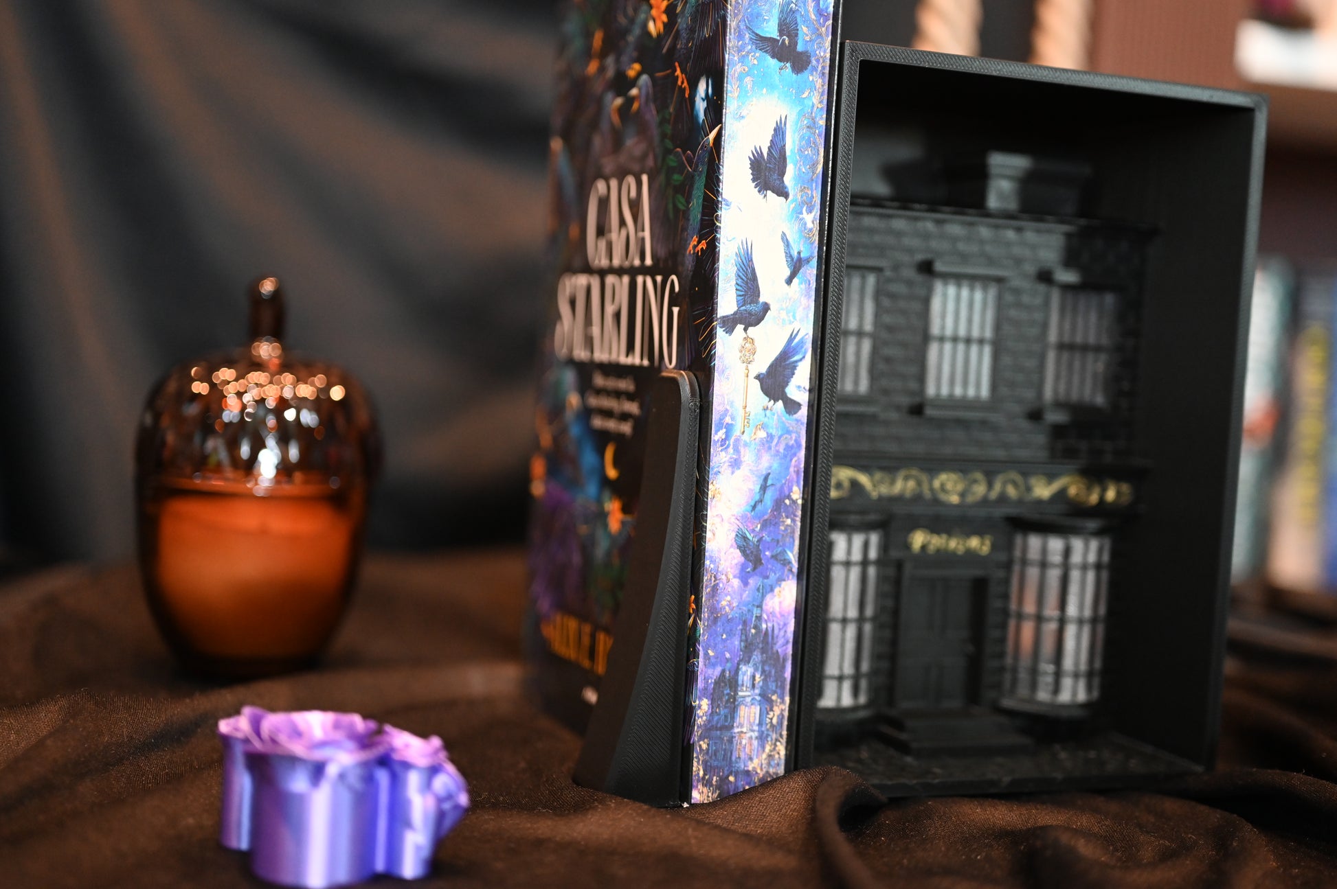 Casa Starling cu printed edges care ilustrează un stol de păsări în zbor deasupra unui castel luminat, în nuanțe de albastru și violet.