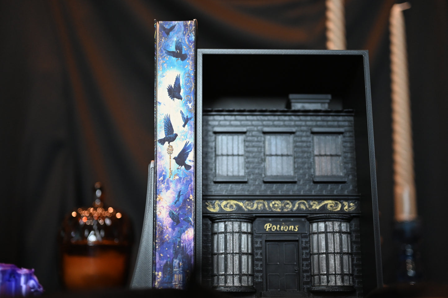 Cartea Casa Starling cu margini imprimate care ilustrează un stol de păsări în zbor deasupra unui castel luminat, în nuanțe de albastru și violet.