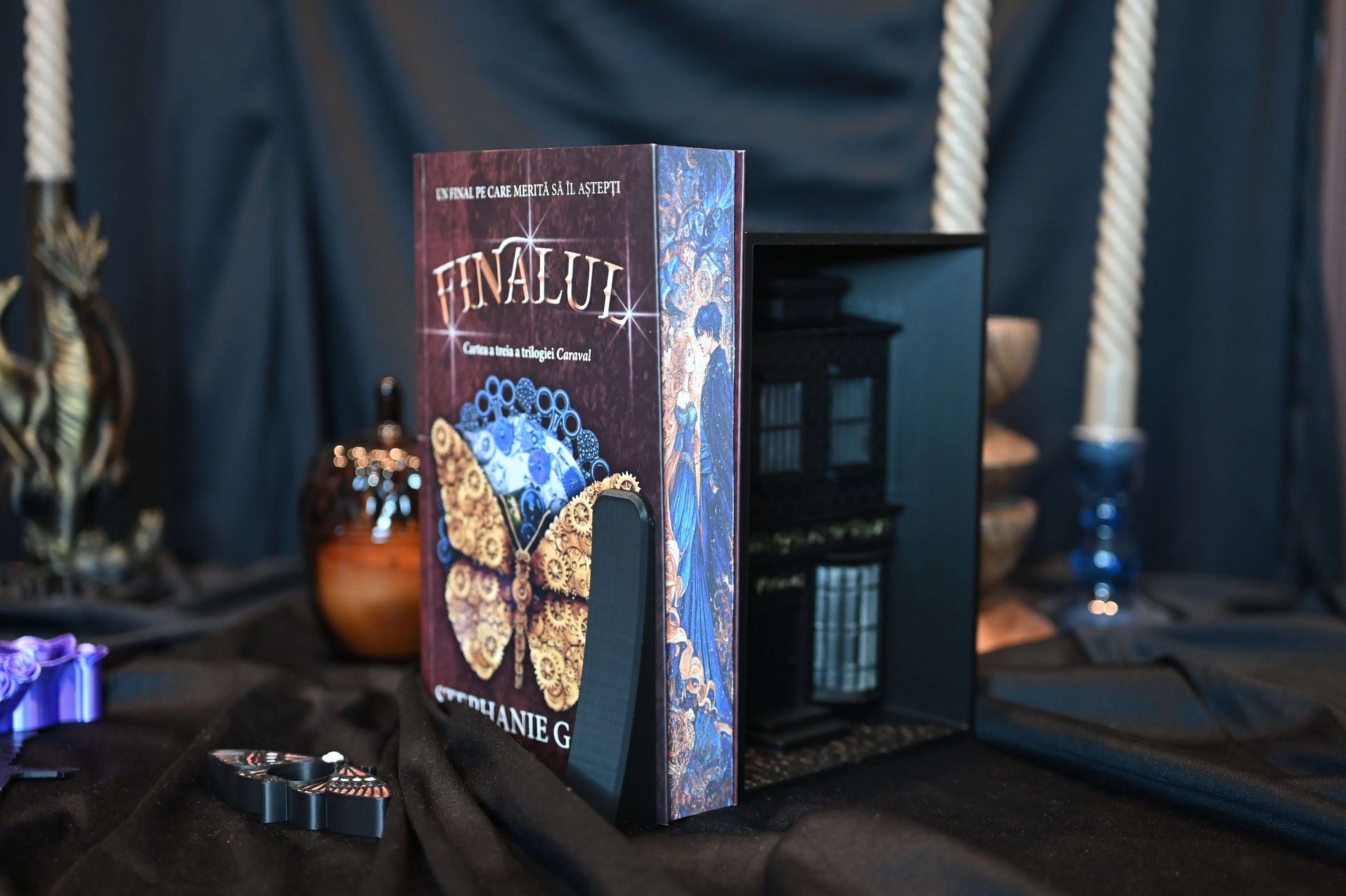 Cartea "Finalul" cu printed edgesde Stephanie Garber, ediție specială cu margini imprimate (printed edges), așezată pe fundal negru cu decoruri elegante și lumânări.