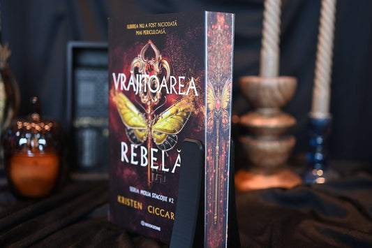 Cartea Vrăjitoarea rebelă cu printed edges de Kristen Ciccarelli, ediție specială cu margini imprimate (printed edges) ilustrând o molie aurie și detalii baroce roșu-aurii, în decor fantasy elegant.