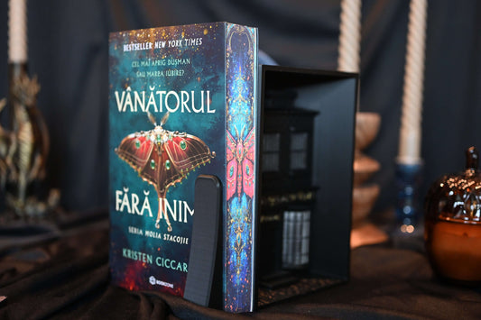 Cartea Vânătorul fără inimă cu printed edges  de Kristen Ciccarelli, ediție specială cu margini imprimate (printed edges) ilustrând o molie roșie și detalii aurii pe fundal albastru intens.