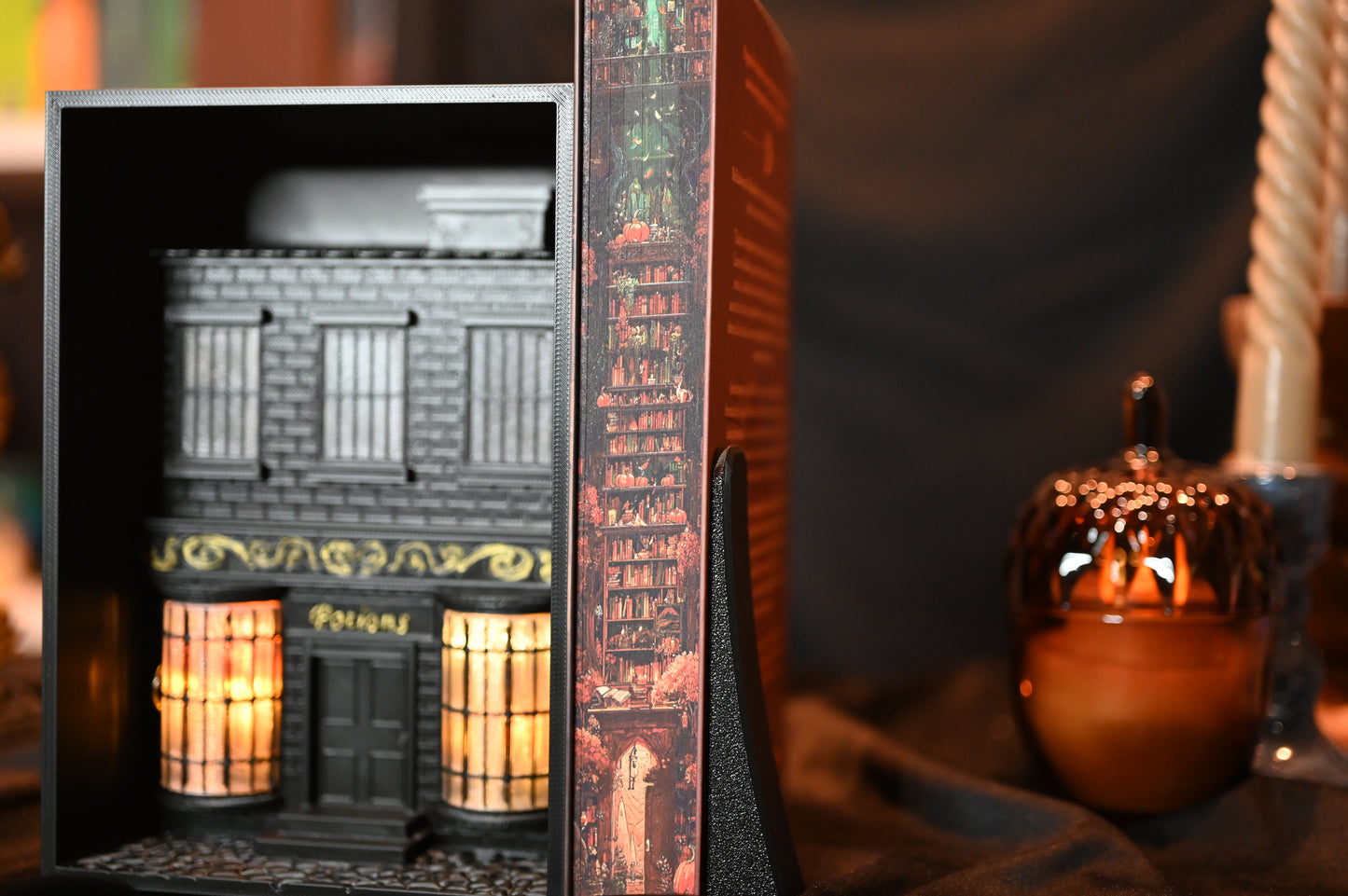 Revrăjită cu printed edges de Lucy Jane Wood, ediție specială cu printed edges. Ilustrația imprimată pe margini prezintă o bibliotecă în nuanțe calde de roșu și portocaliu, cu rafturi pline de cărți și elemente magice ascunse printre ele.