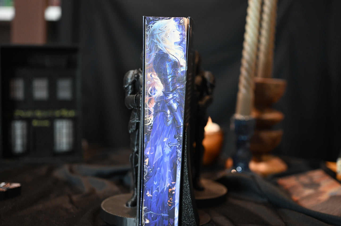 Cartea Cavalerul și Molia de Rachel Gillig, ediție specială cu printed edges. Coperta prezintă o femeie cu părul auriu și ochii acoperiți, iar pe marginea cărții se vede o ilustrație în nuanțe de albastru cu o siluetă în armură