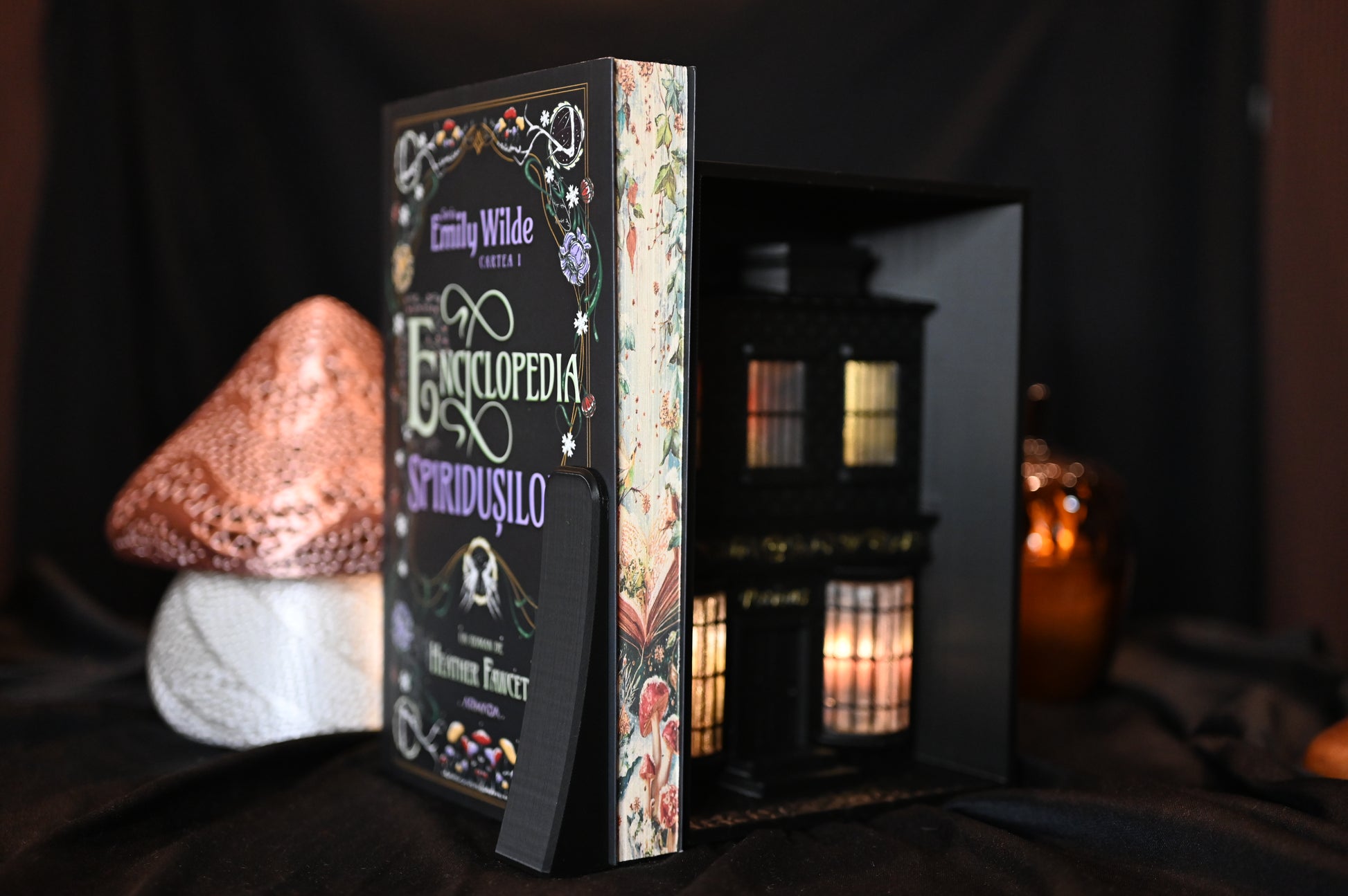 Cartea Enciclopedia spiridușilor de Heather Fawcett, ediție specială cu printed edges. Coperta decorată cu motive florale și titlu în stil victorian, iar marginile paginilor prezintă ilustrații delicate cu ciuperci și flori pe fundal deschis, inspirate din natură.