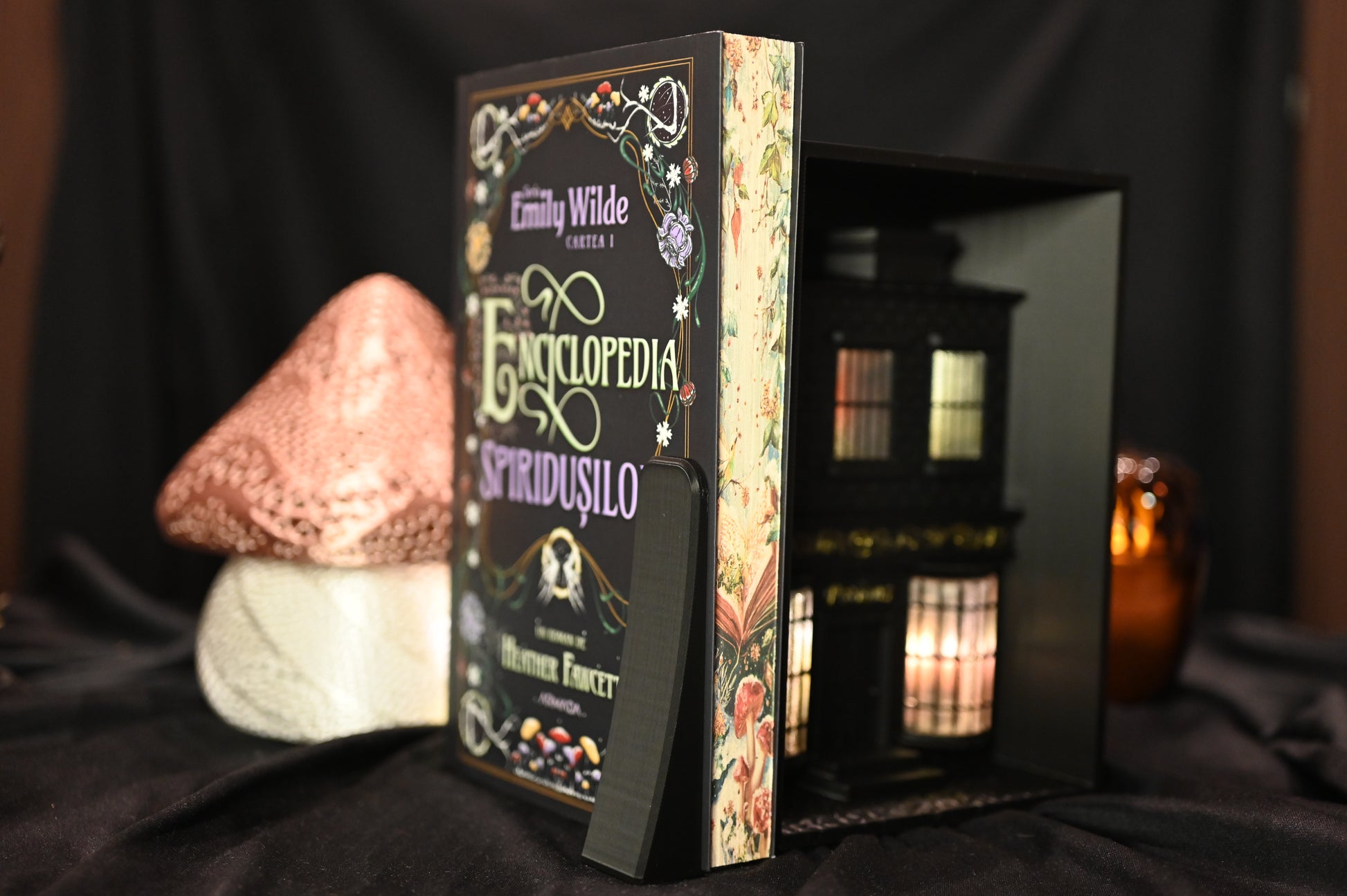 Cartea Enciclopedia spiridușilor de Heather Fawcett, ediție specială cu printed edges. Coperta decorată cu motive florale și titlu în stil victorian, iar marginile paginilor prezintă ilustrații delicate cu ciuperci și flori pe fundal deschis, inspirate din natură.