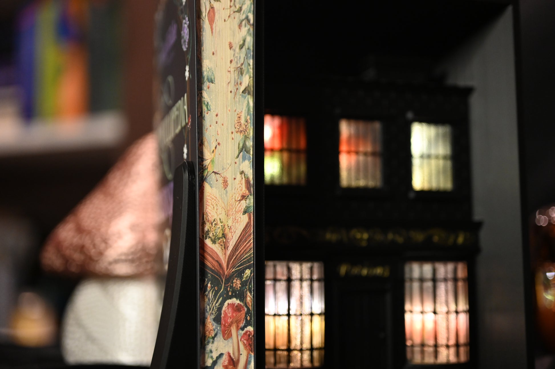 Cartea Enciclopedia spiridușilor de Heather Fawcett, ediție specială cu printed edges. Coperta decorată cu motive florale și titlu în stil victorian, iar marginile paginilor prezintă ilustrații delicate cu ciuperci și flori pe fundal deschis, inspirate din natură.