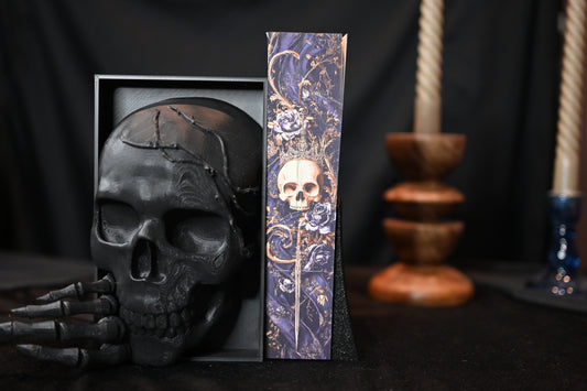 The Book of Azrael cu printed edges - Amber V. Nicole next to a decorative skull on a dark background.