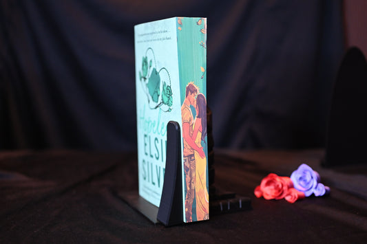 Cartea Hopeless cu printed edges de Elsie Silver, ediție cu margini imprimate verde-mentă, înfățișează un cuplu tandru: un bărbat în cămașă deschisă la culoare și o femeie satena în rochie galbenă se îmbrățișează romantic. Marginea are un trandafir verde și un lanț subțir