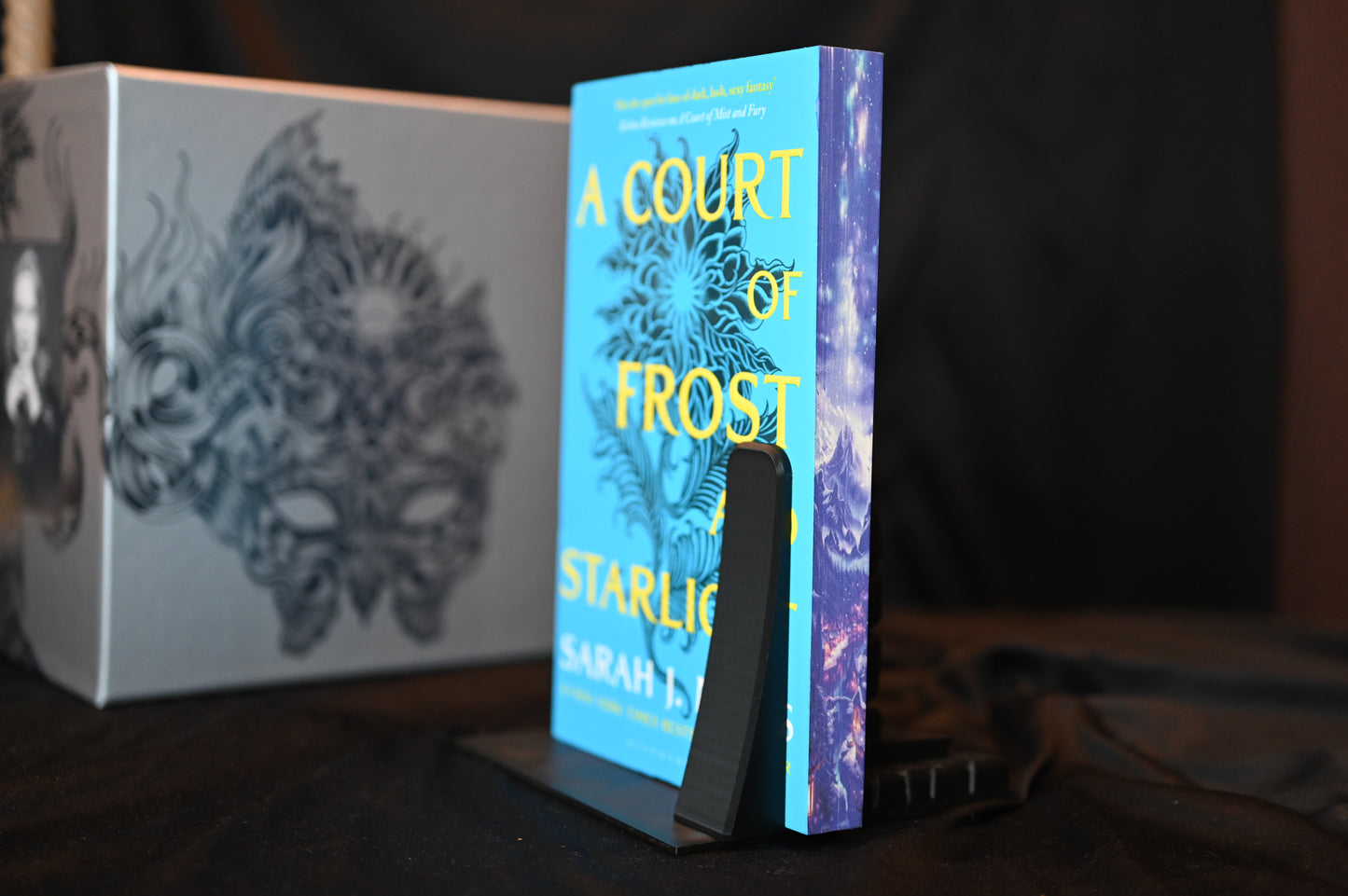 Set Acotar cu printed edges Cartea A Court of Frost and Starlight cu margini imprimate albastre, ilustrând un peisaj montan sub cer înstelat.