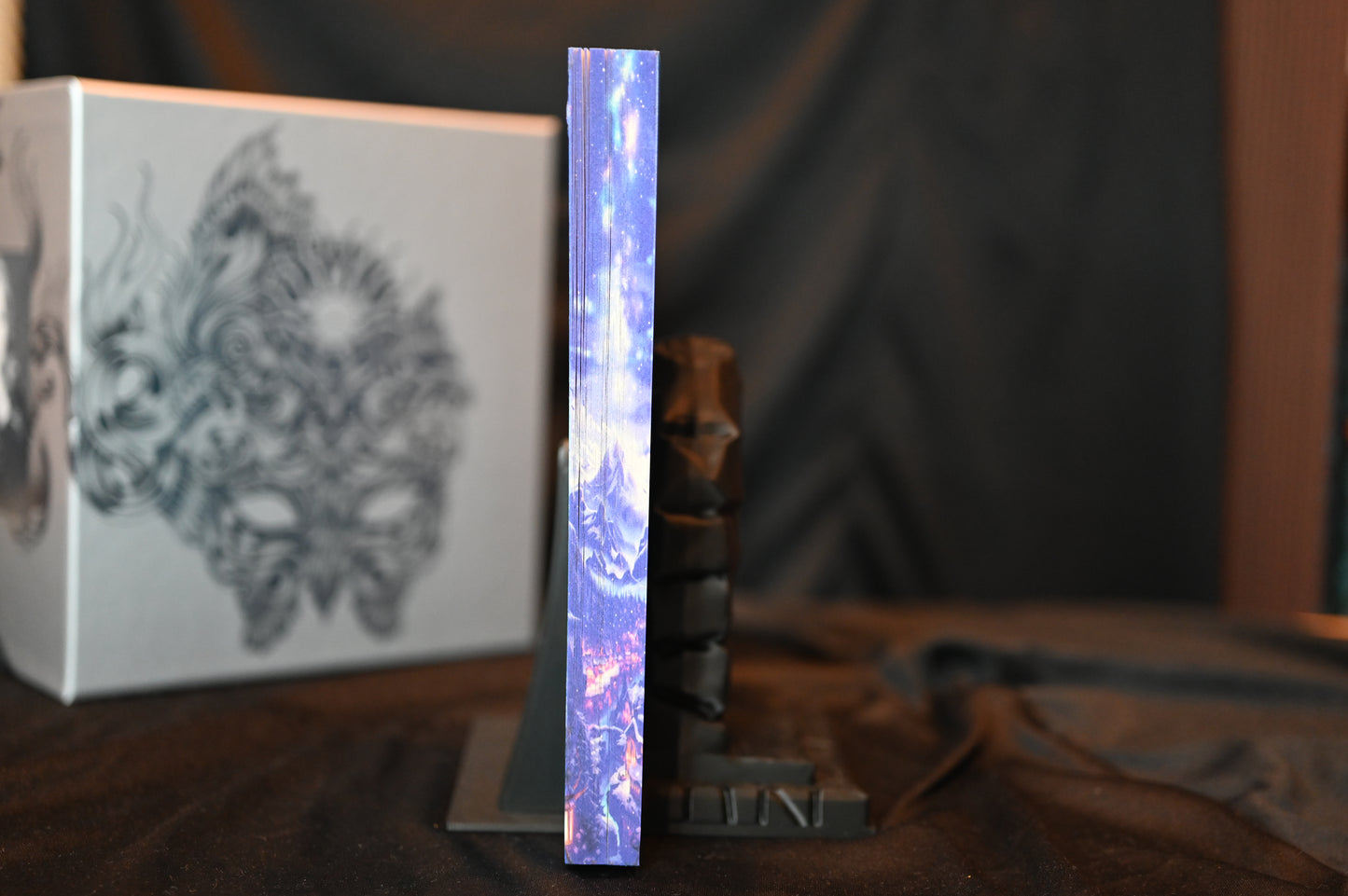 A Court of Frost and Starlight cu printed edges cu margini imprimate albastre, ilustrând un peisaj montan sub cer înstelat.