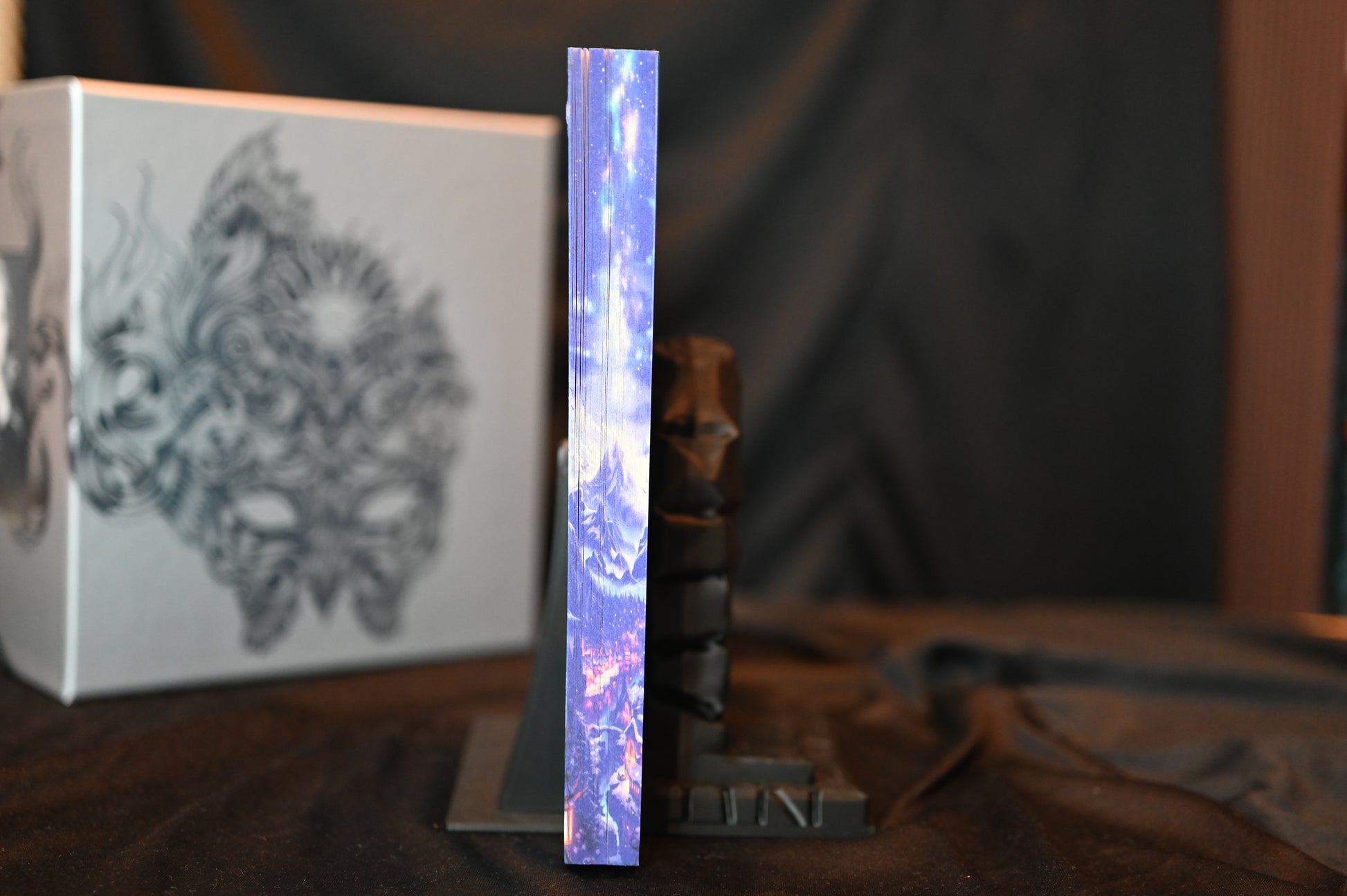 A Court of Frost and Starlight cu printed edges cu margini imprimate albastre, ilustrând un peisaj montan sub cer înstelat.