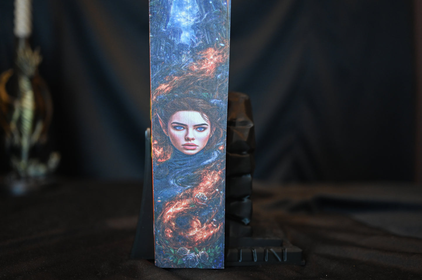 Cartea A Court of Silver Flames cu printed edges de Sarah J. Maas, cu copertă portocalie și margini imprimate ce prezintă portretul unei femei elfice învăluită în flăcări argintii.