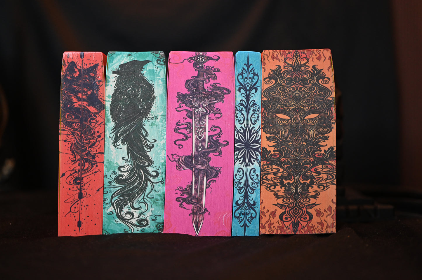 Set ACOTAR cu printed edges – cinci volume cu margini ilustrate artistic: lup, corb, sabie, motiv floral și mască de foc.