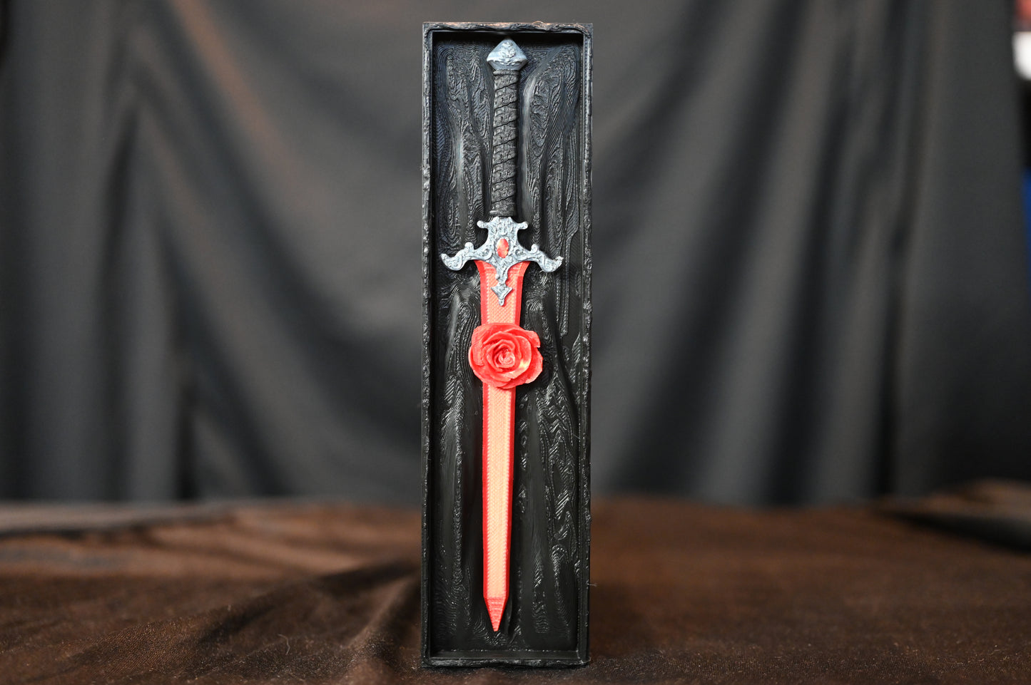 Book nook „The Hidden Rose Sword” – sabie roșie cu trandafir sculptat, așezată într-o cutie decorativă neagră cu textură gotică.