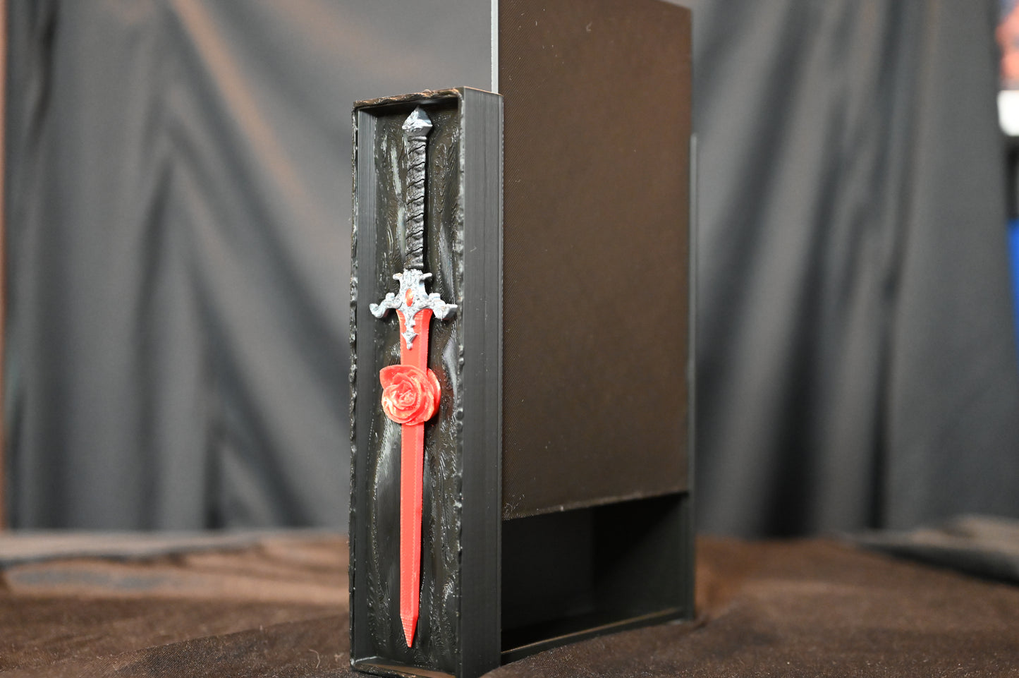Book nook „The Hidden Rose Sword” de Print Edges – sabie roșie cu trandafir sculptat într-o cutie decorativă neagră.