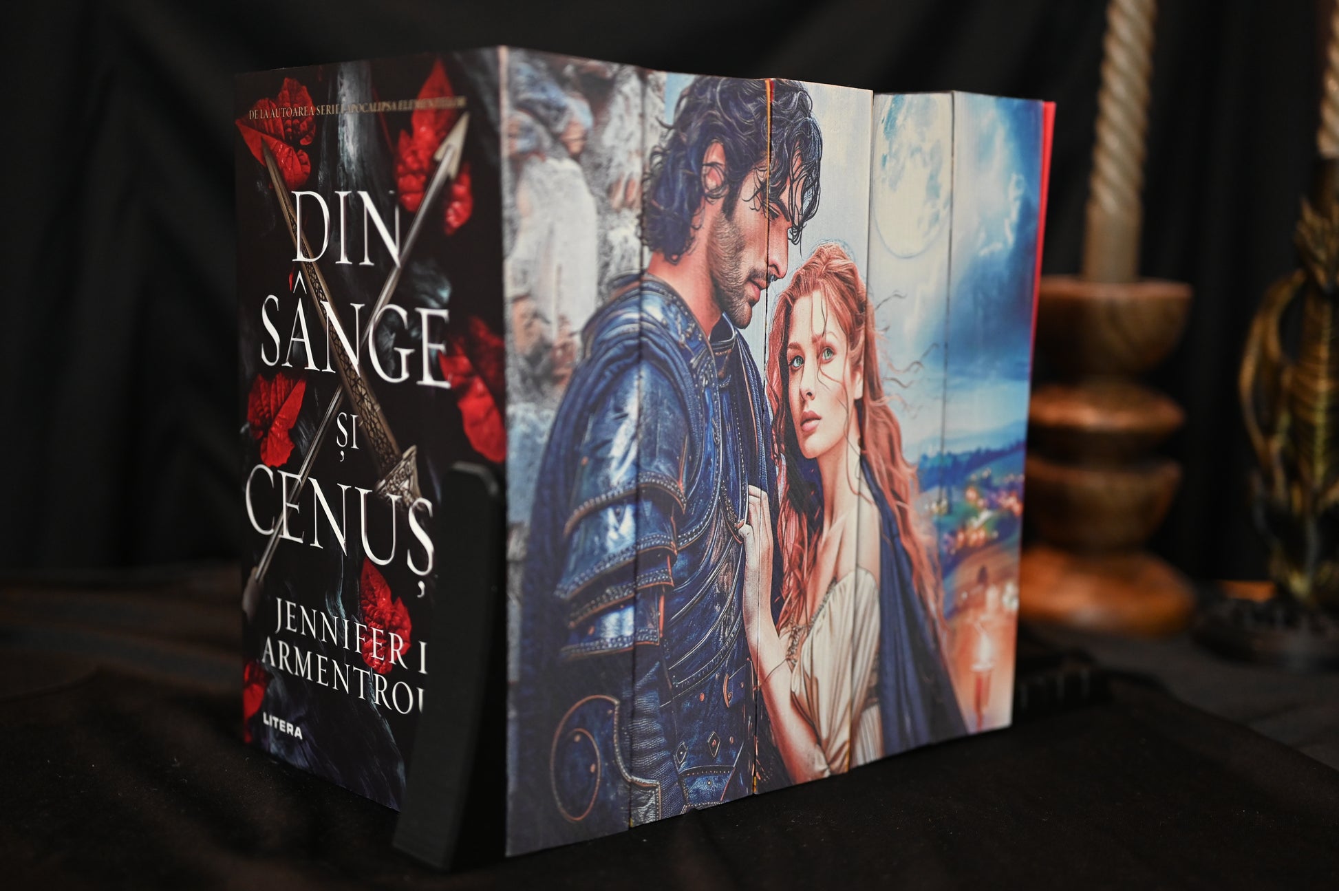 Set Din sânge și cenușă - 5 volume cu printed edges, prezentând o ilustrație detaliată cu un bărbat în armură și o femeie cu păr roșcat și ochi verzi, sub o lună plină, pe un fundal de peisaj nocturn.