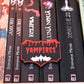 Etichetă 3D Vampires, neagră cu margini roșii, litere roșii care par scurse și un liliac alb cu ochi roșii în partea de jos.