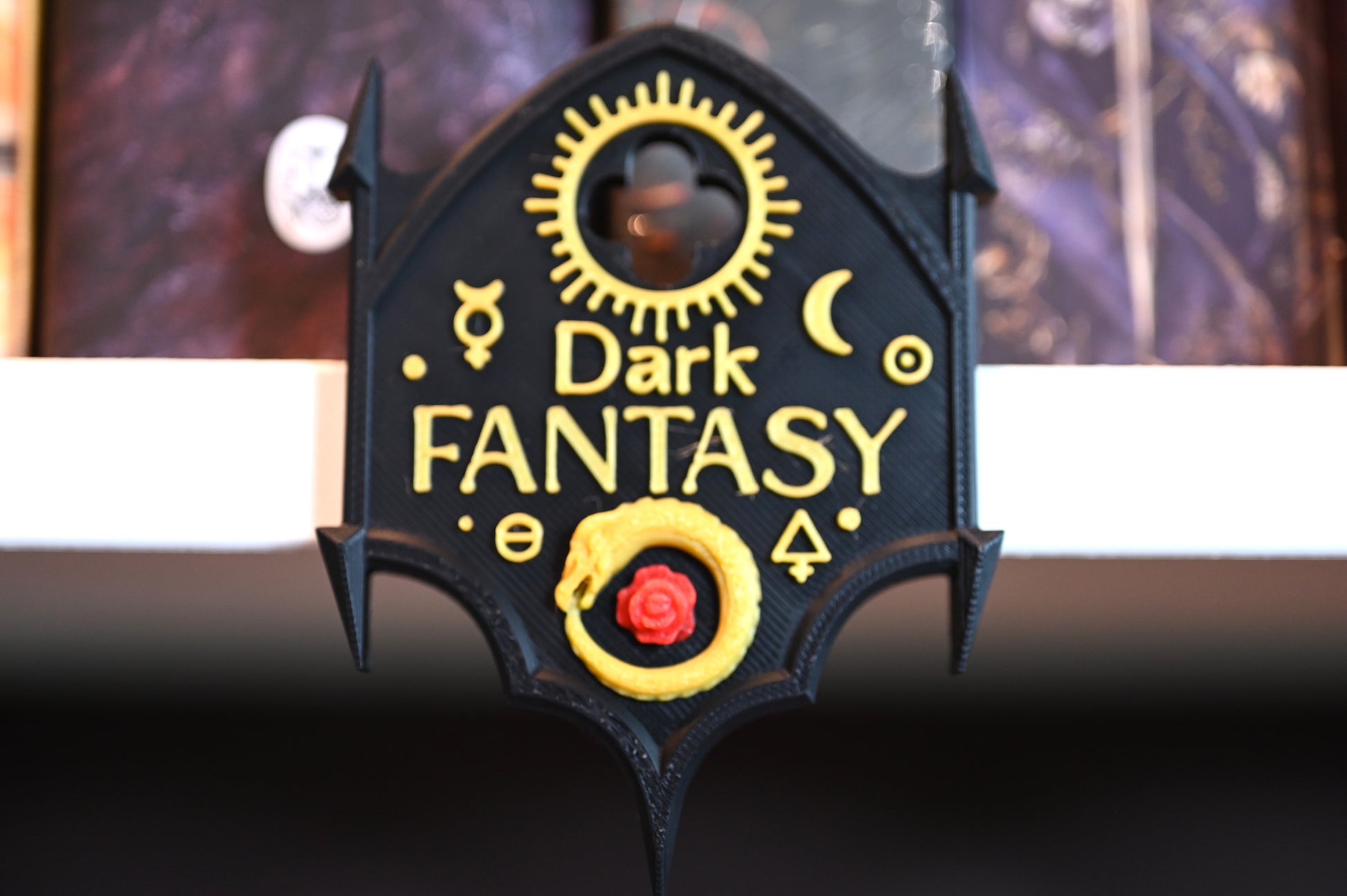 Etichetă 3D pentru genul Dark Fantasy, în formă de arc gotic negru cu detalii aurii, simboluri magice și un șarpe ouroboros galben cu o floare roșie.