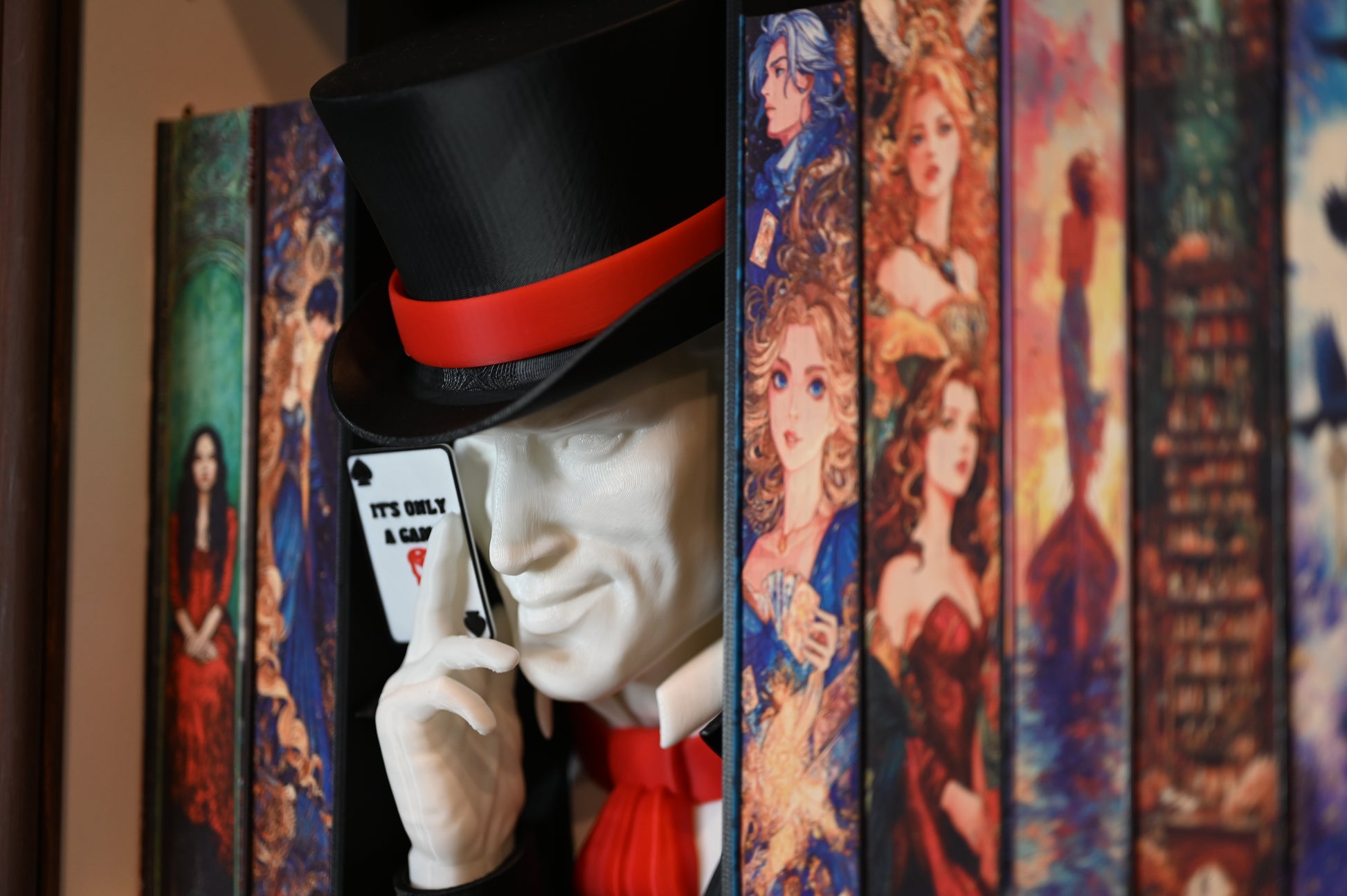 Book nook inspirat din Legend din Caraval, încadrat între cărți cu coperți ilustrate fantasy, cu joben negru și cartelă ‘It’s Only a Game’ în mână.