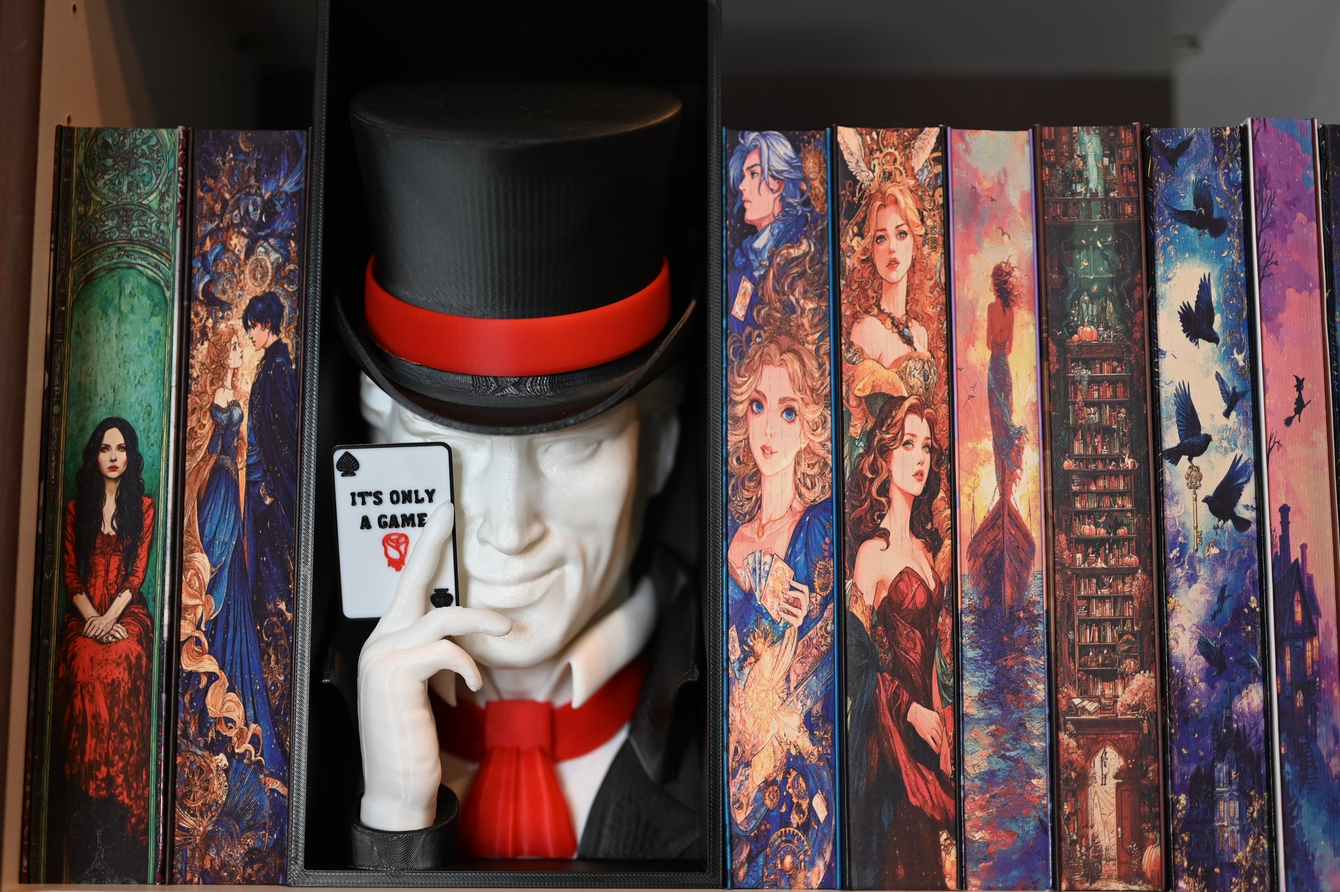 Book nook inspirat din Legend din Caraval, încadrat între cărți cu coperți ilustrate fantasy, cu joben negru și cartelă ‘It’s Only a Game’ în mână.