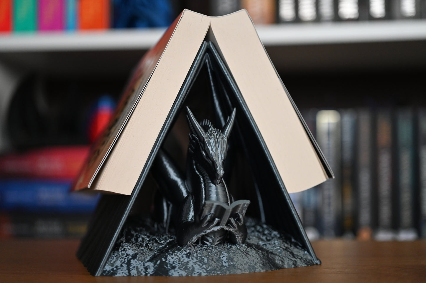 Suport decorativ pentru bibliotecă cu forma de dragon care sustine o carte scrisa de Rebecca Yarros