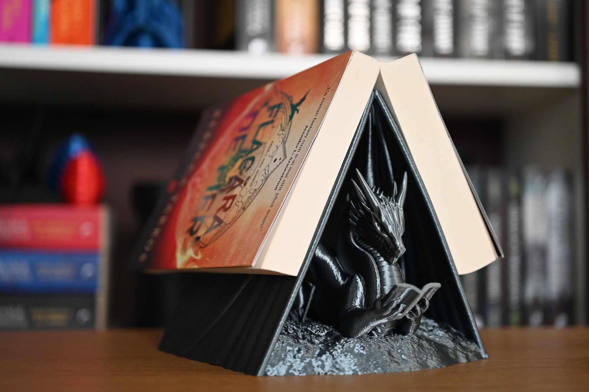 suport cu forma de dragon care sustine o carte scrisa de Rebecca Yarros