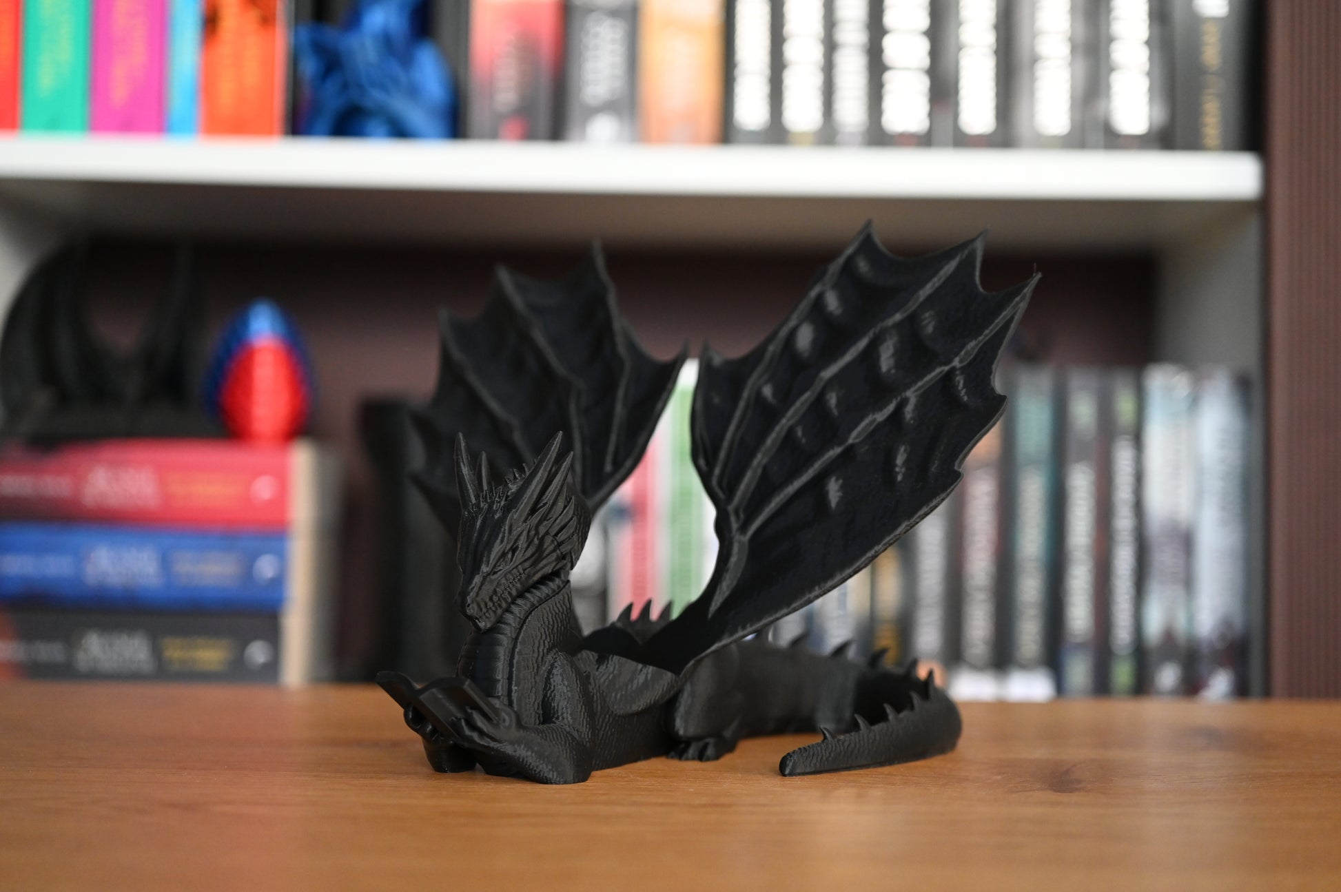 Book Holder Decorativ  dragon negru cu aripi mari in fata unei biblioteci