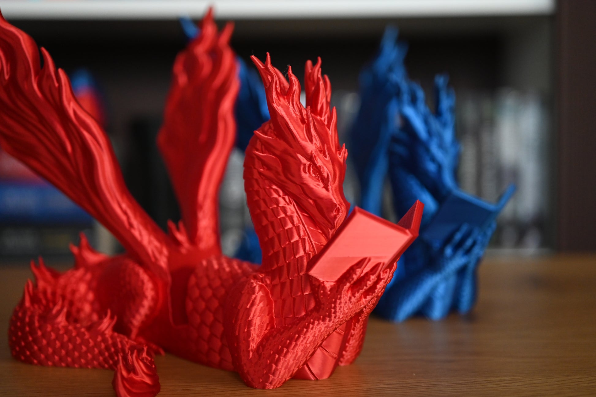 Suport pentru Kindle un dragon albastru si unul rosu in fata unei biblioteci