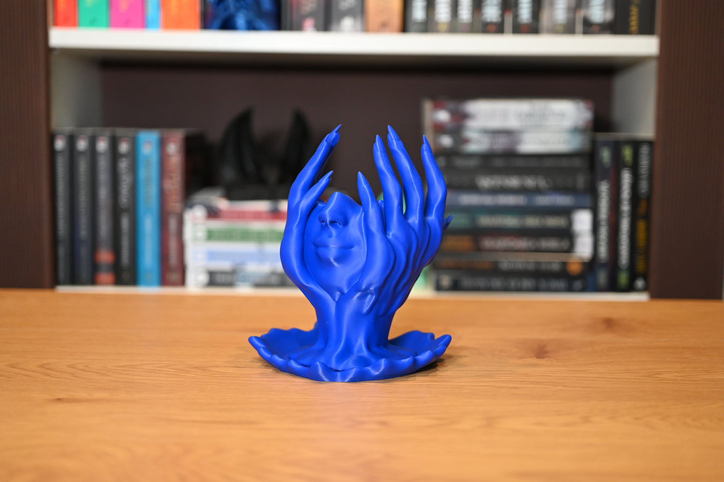 Obiect decorativ fantasy cu fata umana sprijinita in maini si pare ca se topeste