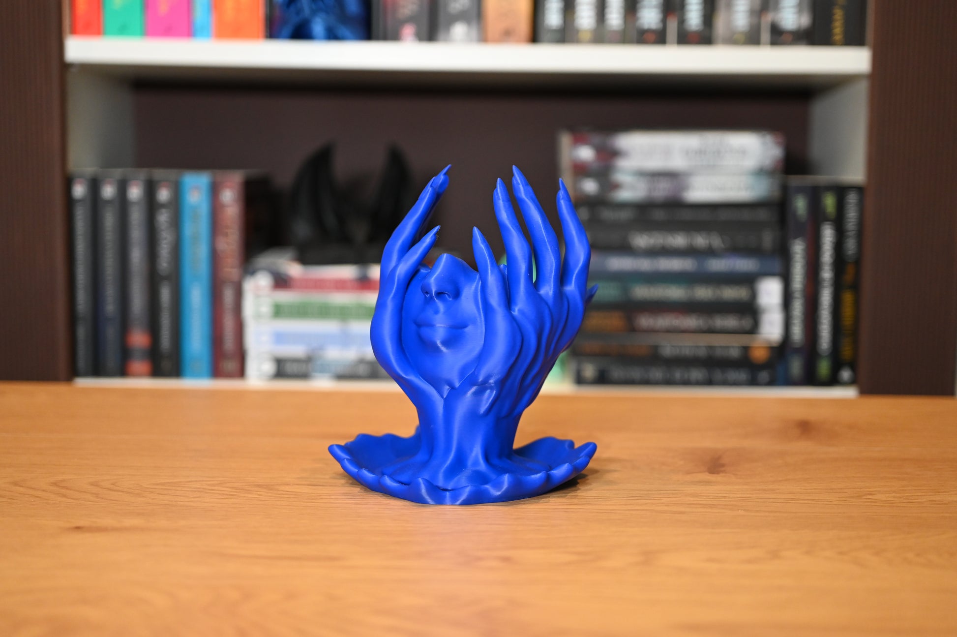 Obiect decorativ fantasy cu fata umana sprijinita in maini si pare ca se topeste