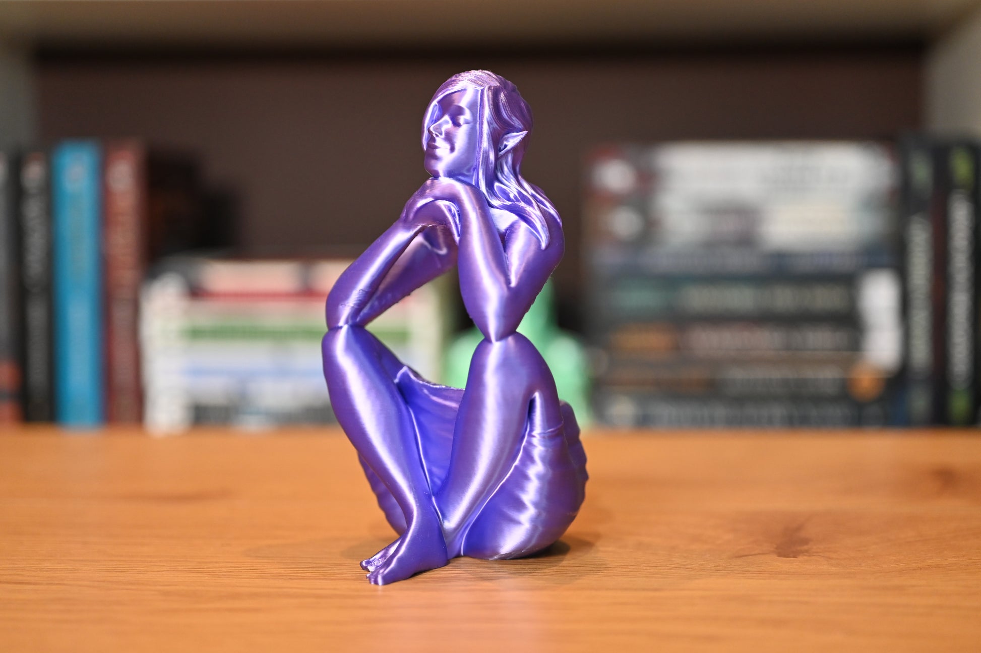 figurina in forma de elf mov stand in fata raftului cu carti fantasy