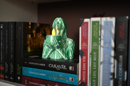 Statuetă fantasy 3D cu bustul unei femei folosit ca suport decorativ de lumanare led, asezate intre cartile unei biblioteci, creand o atmosfera cozy