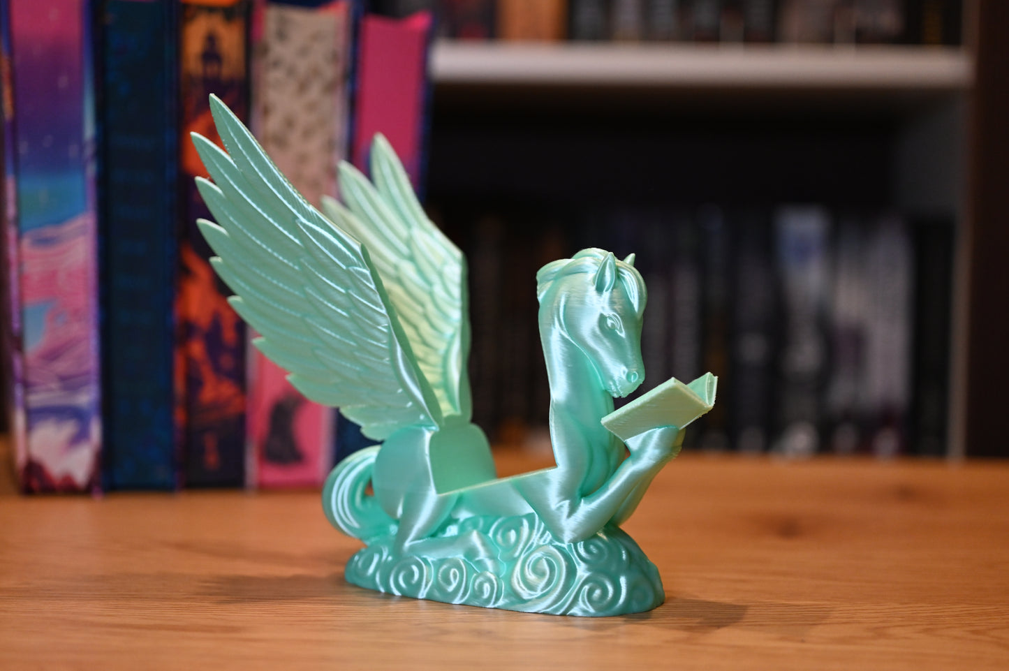 Suport pentru Kindle sau cărți cu forma lui Pegasus asezat in fata unui raft cu carti