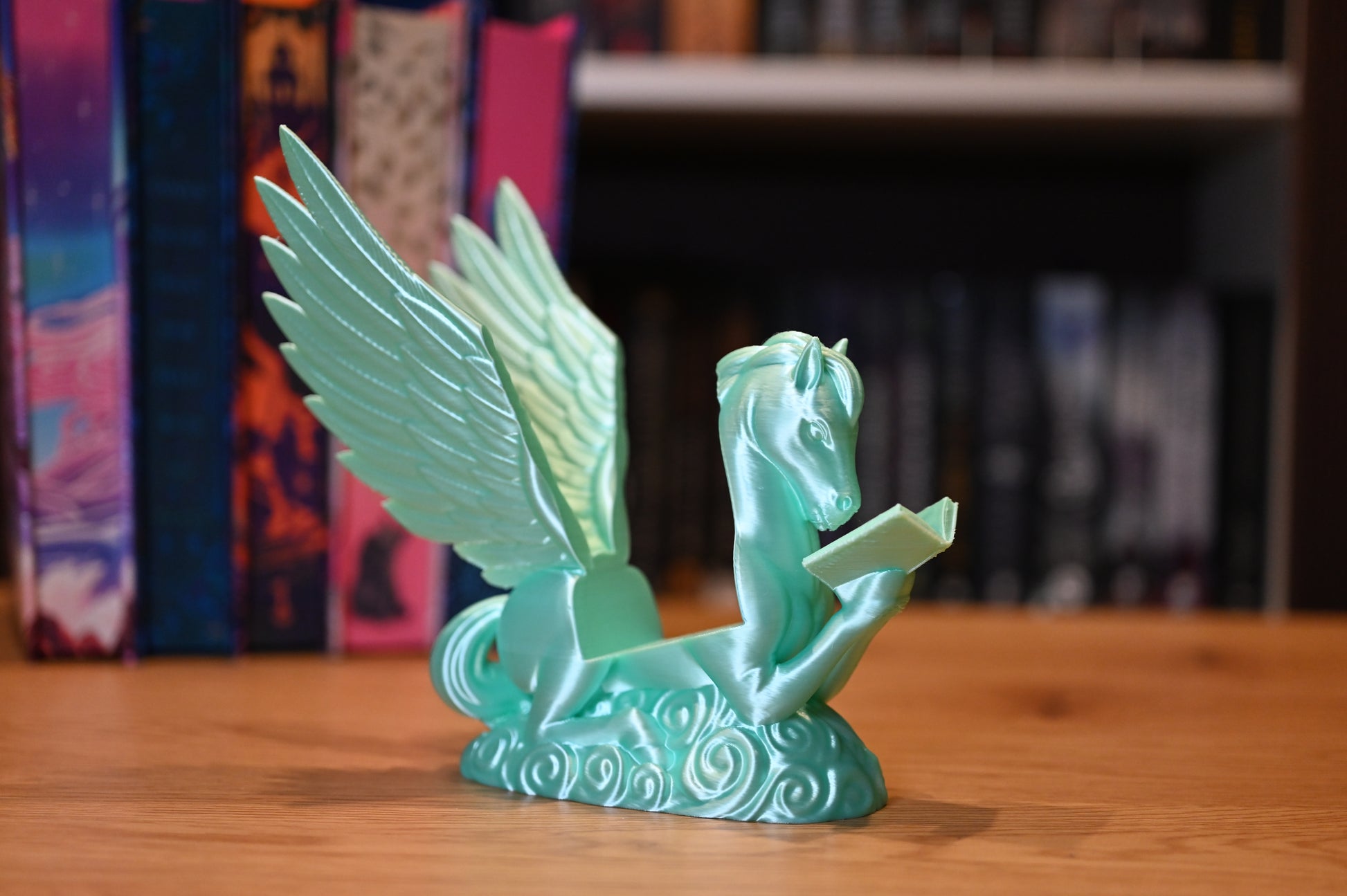 Suport pentru Kindle sau cărți cu forma lui Pegasus asezat in fata unui raft cu carti