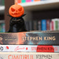 Figurină 3D Halloween  cu un dovleac ce poarta pelerina si are o carte in mana, asezat pe un teanc de carti scrise de Stephen King
