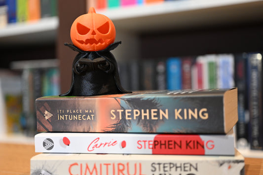Figurină 3D Halloween  cu un dovleac ce poarta pelerina si are o carte in mana, asezat pe un teanc de carti scrise de Stephen King