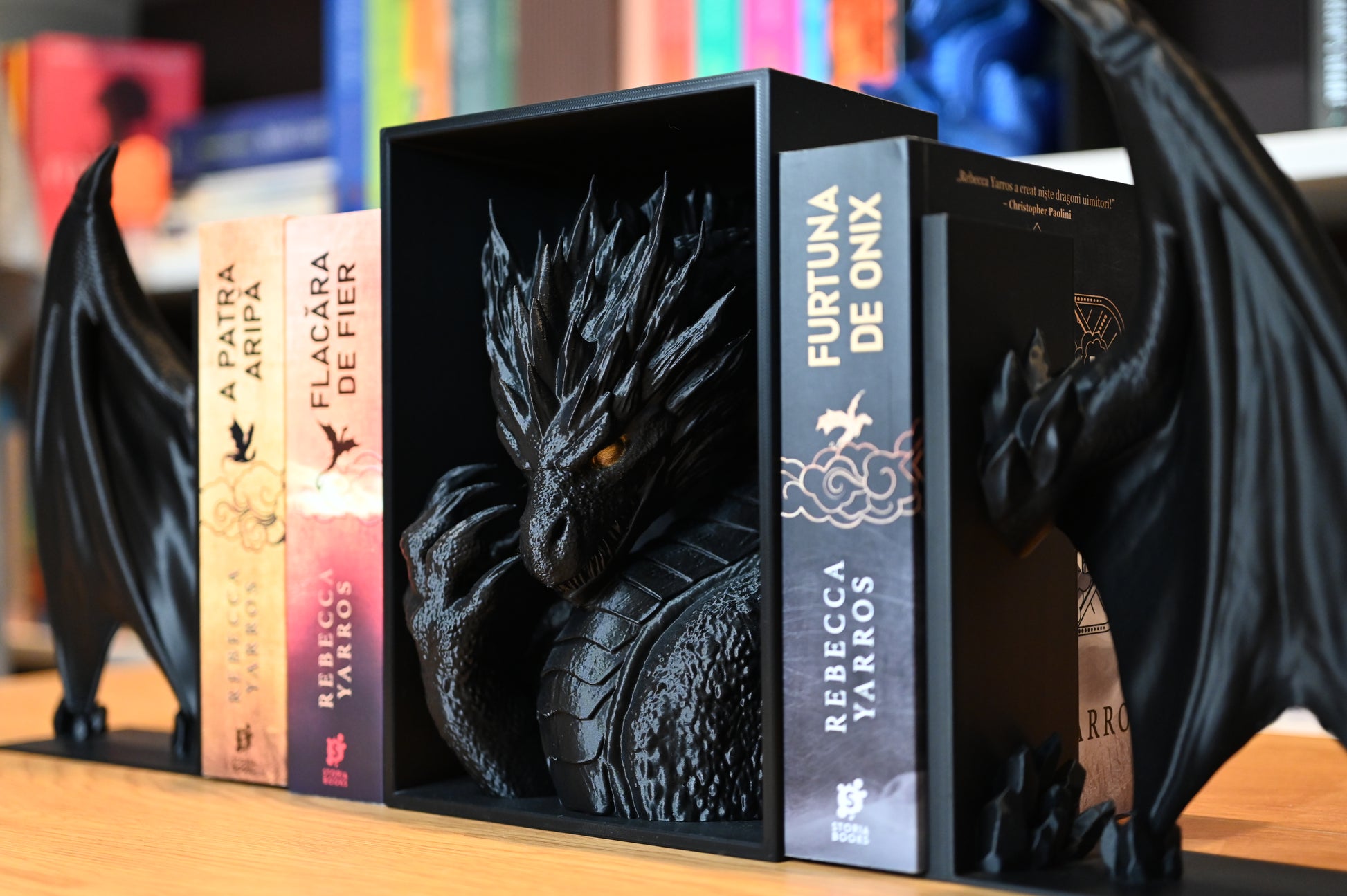 Decor fantasy cu dragon negru între romanele A Patra Aripă, Flacără de Fier și Furtuna de Onix de Rebecca Yarros.